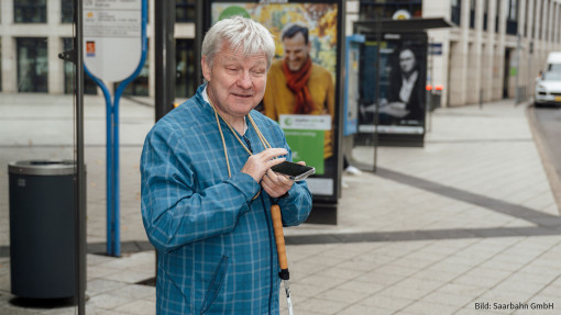 Bilder Fahrgast mit Smartphone an einer Bushaltestelle